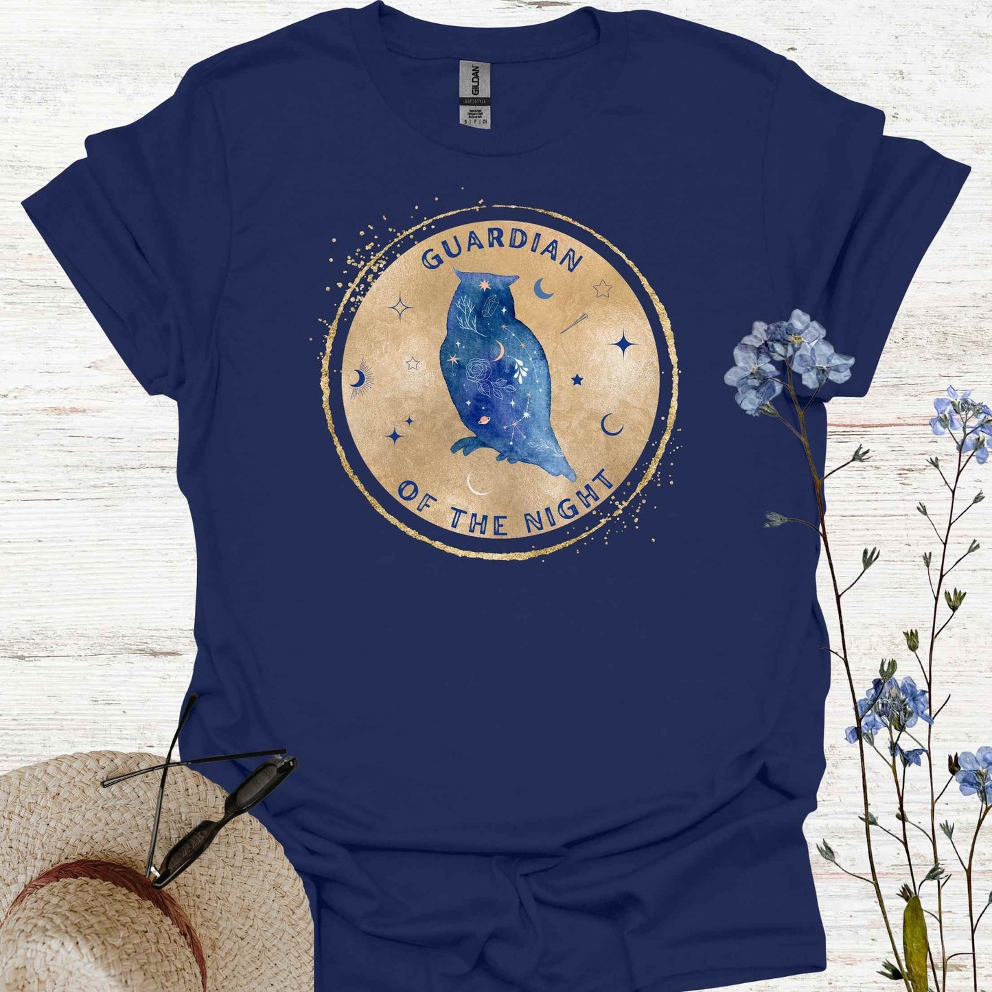 Navy blue t-shirt design featuring a blue owl perched on a gold circular background with mystical symbols, accompanied by the phrase 'Guardian of the Night.' The owl, a symbol of wisdom, intuition, and protection, embodies a deep connection to the mysteries of the night and the unseen. Perfect for those who resonate with themes of introspection, spirituality, and nature's mystique.