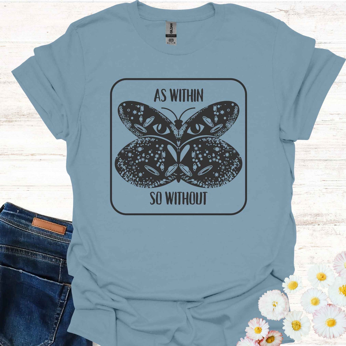 Blue t-shirt featuring a detailed graphic of a butterfly with cosmic and universal symbols on its wings, paired with the philosophical phrase 'As Within So Without.' This design reflects the idea that the external world is a reflection of our inner selves, symbolizing the interconnectedness of the universe and our own universal consciousness.