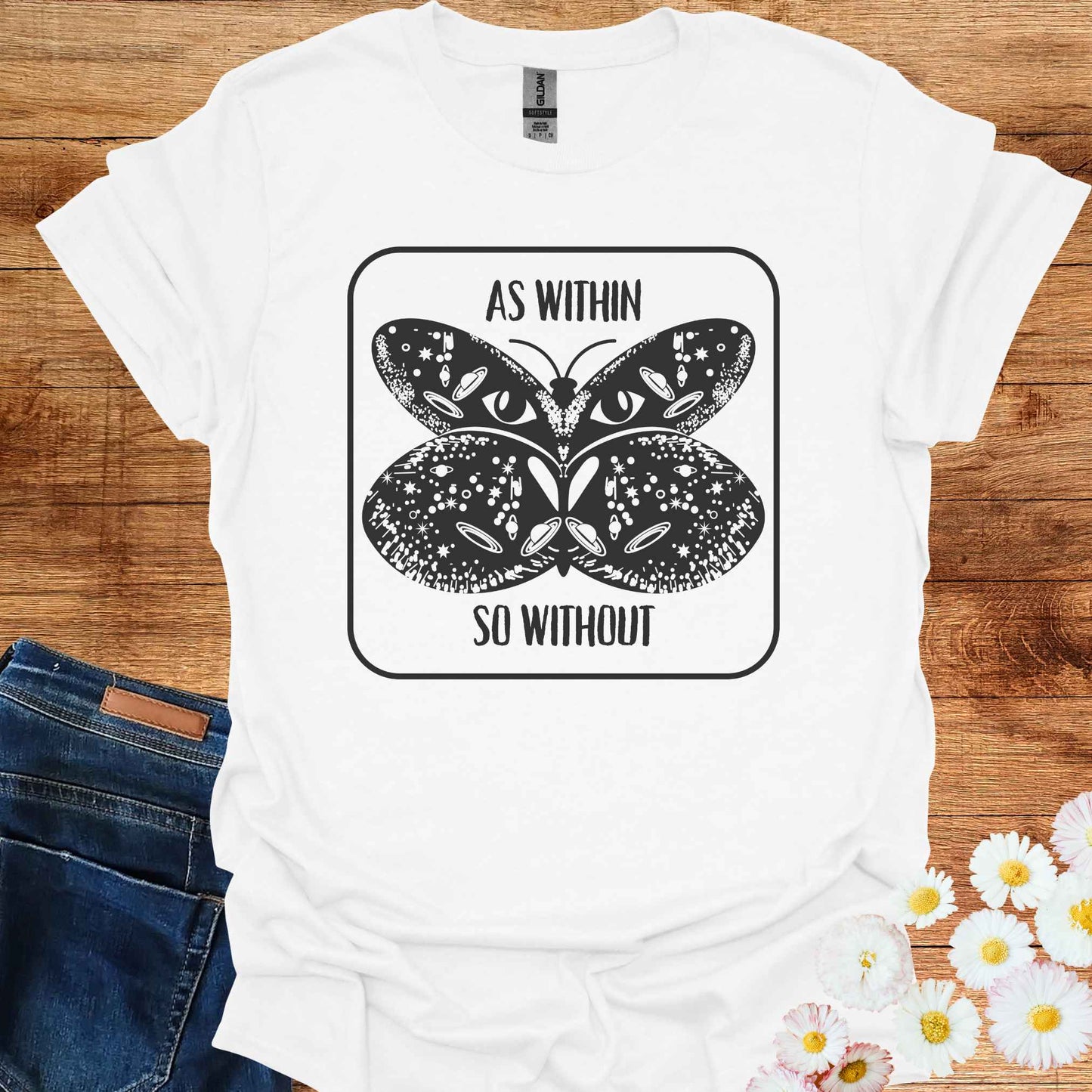 White t-shirt featuring a detailed graphic of a butterfly with cosmic and universal symbols on its wings, paired with the philosophical phrase 'As Within So Without.' This design reflects the idea that the external world is a reflection of our inner selves, symbolizing the interconnectedness of the universe and our own universal consciousness.
