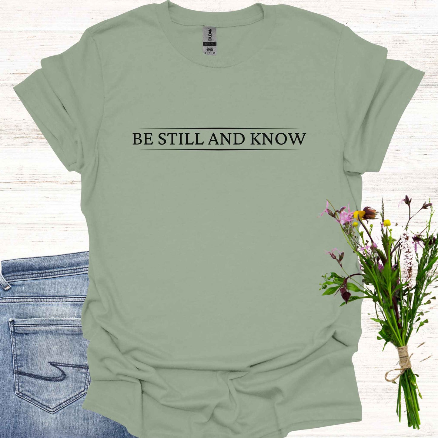 Simple sage green t-shirt featuring the spiritual phrase 'Be Still and Know' in clean, minimalist typography. This design encourages inner stillness and self-awareness, reminding meditators and spiritual seekers to find peace within and realize the truth of their being.