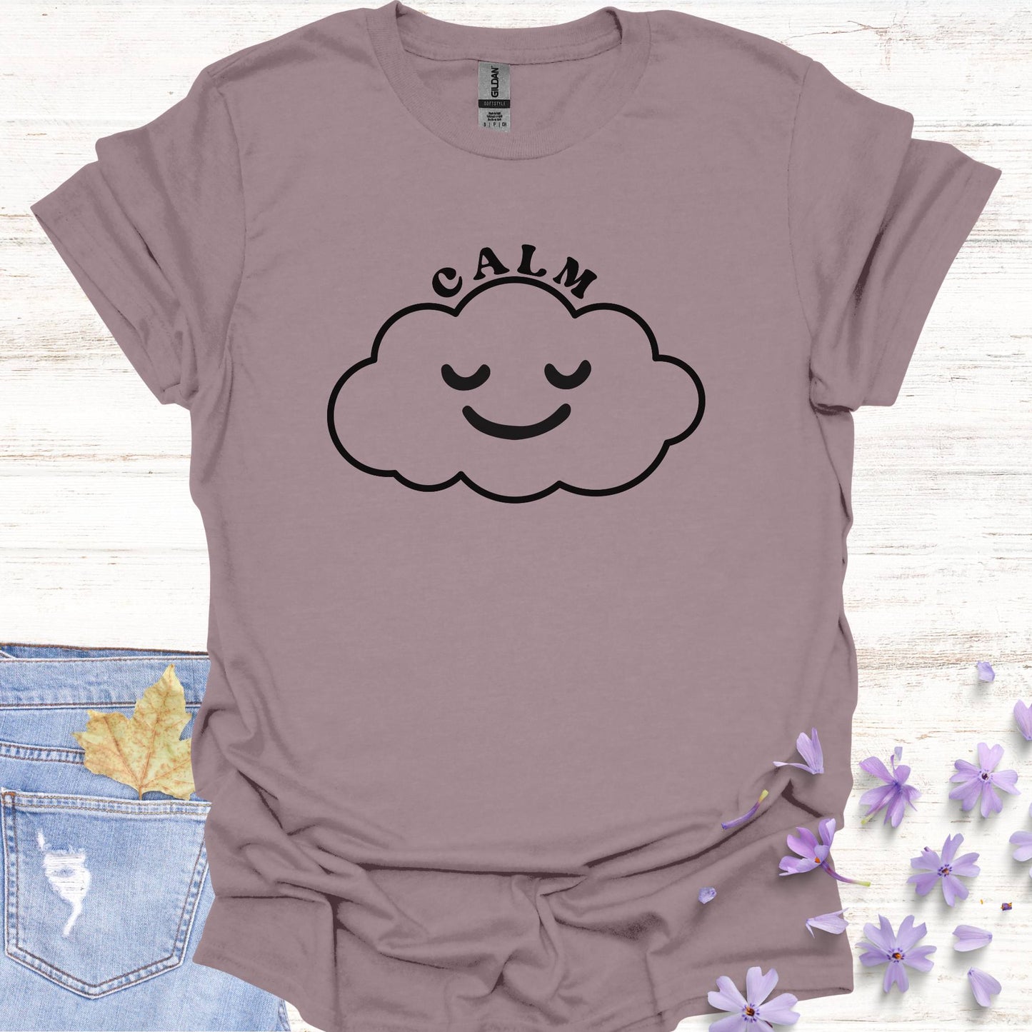 Light purple t-shirt featuring design of a minimalist line drawing of a cloud with a serene smiling face inside, accompanied by the word "calm" in bold typography. This design symbolizes inner peace, tranquility, and emotional balance, reminding wearers to embrace calmness in the midst of life's challenges. Perfect for the personal growth enthusiasts, it inspires mindfulness, self-reflection, and a sense of ease.