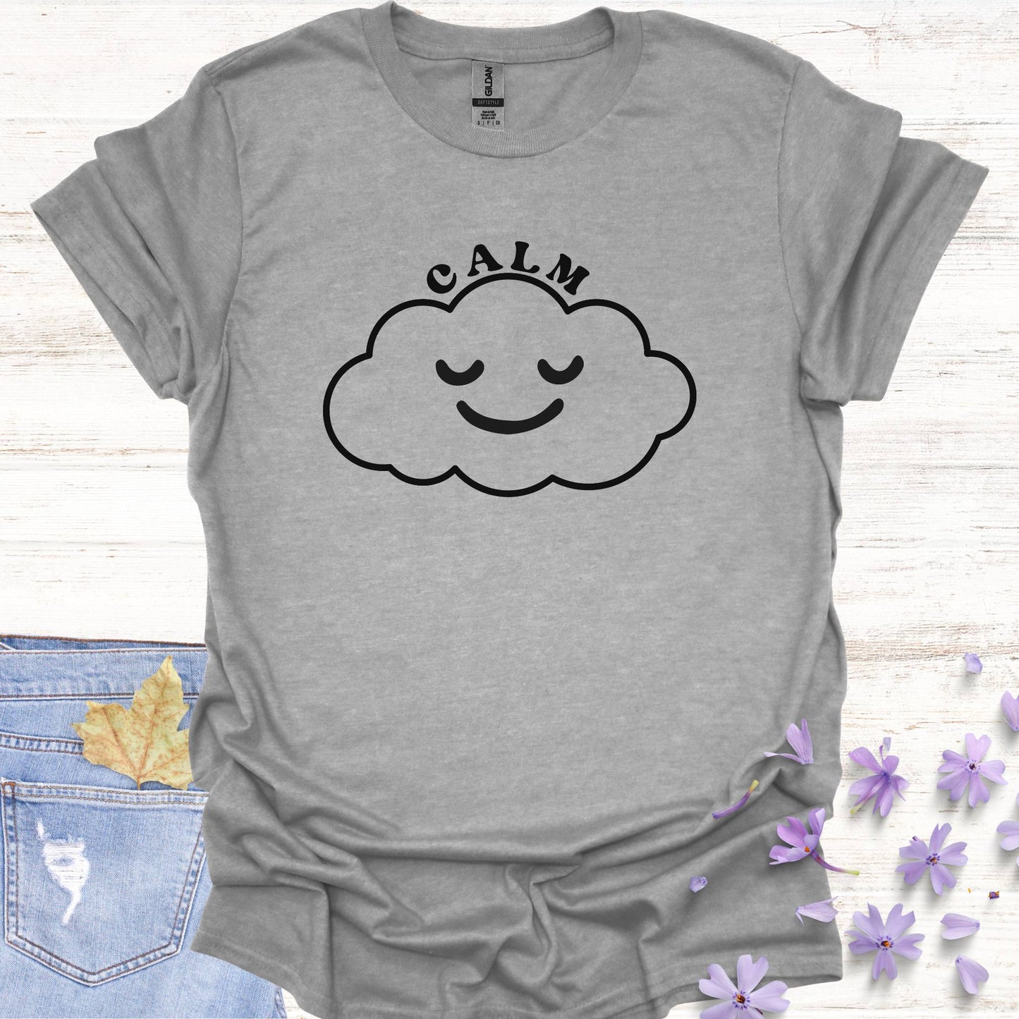Grey t-shirt featuring design of a minimalist line drawing of a cloud with a serene smiling face inside, accompanied by the word "calm" in bold typography. This design symbolizes inner peace, tranquility, and emotional balance, reminding wearers to embrace calmness in the midst of life's challenges. Perfect for the personal growth enthusiasts, it inspires mindfulness, self-reflection, and a sense of ease.