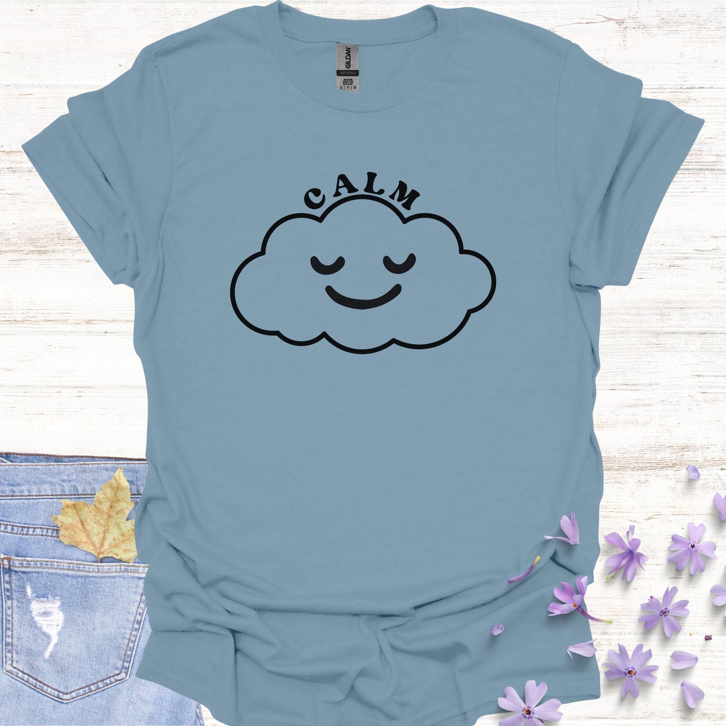 Blue t-shirt featuring design of a minimalist line drawing of a cloud with a serene smiling face inside, accompanied by the word "calm" in bold typography. This design symbolizes inner peace, tranquility, and emotional balance, reminding wearers to embrace calmness in the midst of life's challenges. Perfect for the personal growth enthusiasts, it inspires mindfulness, self-reflection, and a sense of ease.