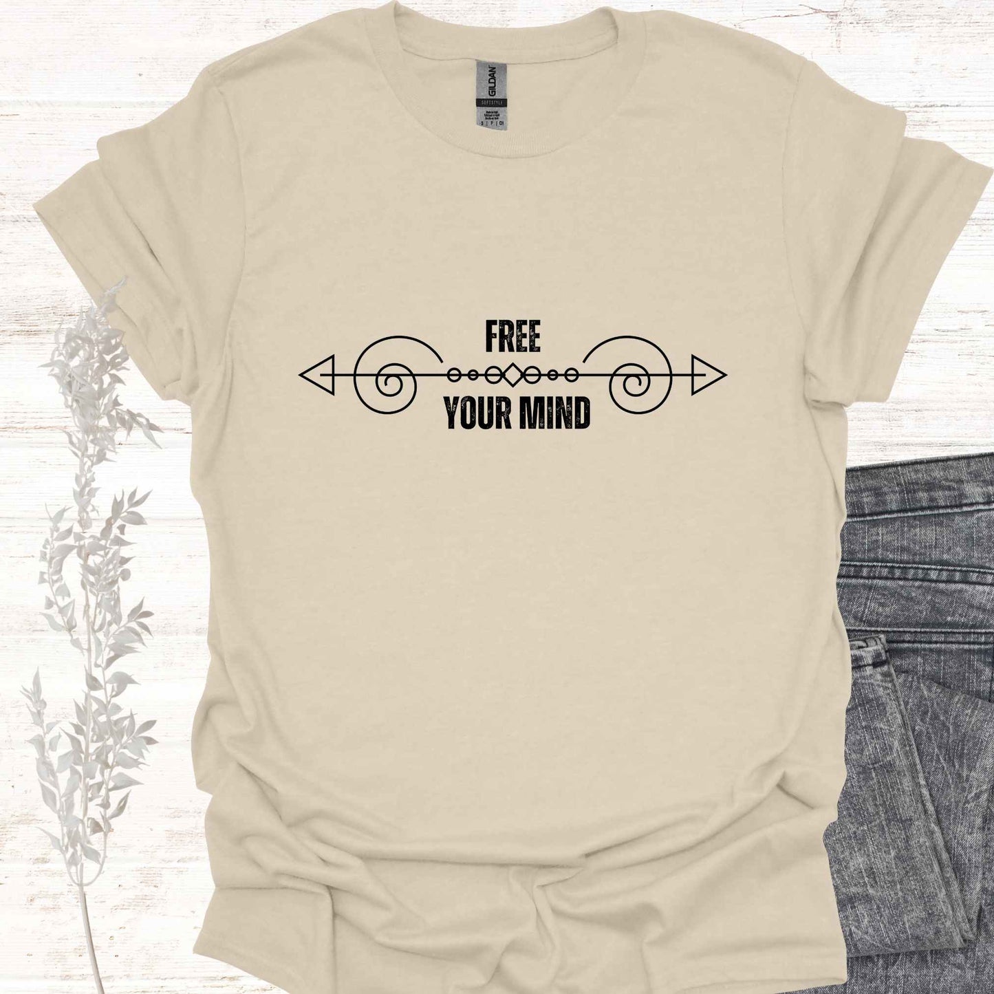 A beige t-shirt featuring a design with a horizontal abstract line graphic symbolizing the flow of thought, paired with the phrase "Free Your Mind" in bold, modern typography. This design references the profound spiritual teaching that the mind itself is the only source of limitation and suffering. By transcending the patterns and constraints of the mind, one can experience true freedom, inner peace, and liberation. Perfect for those on a path of self-discovery, mindfulness, and spiritual growth.