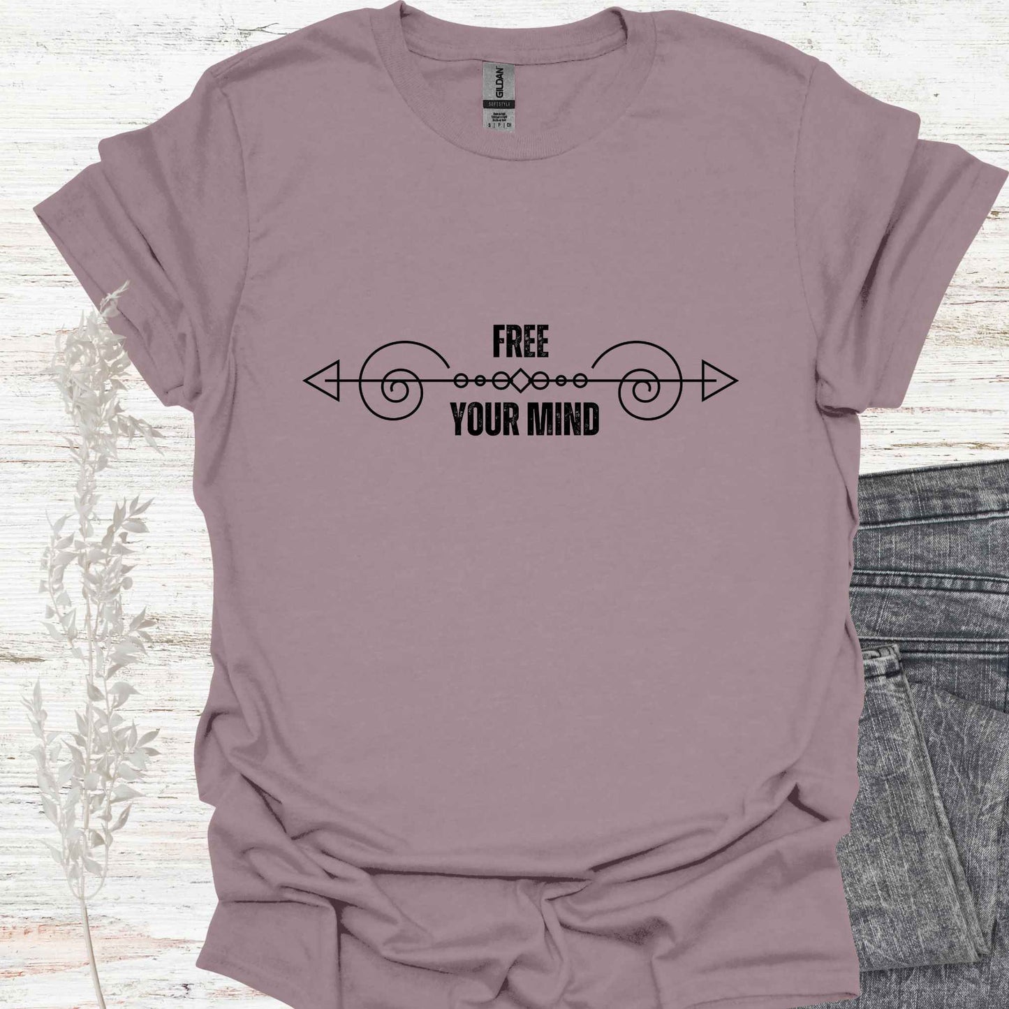A purple t-shirt featuring a design with a horizontal abstract line graphic symbolizing the flow of thought, paired with the phrase "Free Your Mind" in bold, modern typography. This design references the profound spiritual teaching that the mind itself is the only source of limitation and suffering. By transcending the patterns and constraints of the mind, one can experience true freedom, inner peace, and liberation. Perfect for those on a path of self-discovery, mindfulness, and spiritual growth.