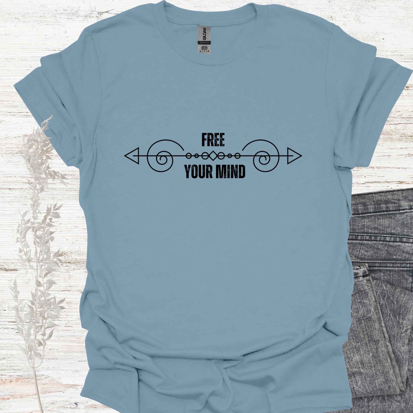 A blue t-shirt featuring a design with a horizontal abstract line graphic symbolizing the flow of thought, paired with the phrase "Free Your Mind" in bold, modern typography. This design references the profound spiritual teaching that the mind itself is the only source of limitation and suffering. By transcending the patterns and constraints of the mind, one can experience true freedom, inner peace, and liberation. Perfect for those on a path of self-discovery, mindfulness, and spiritual growth.