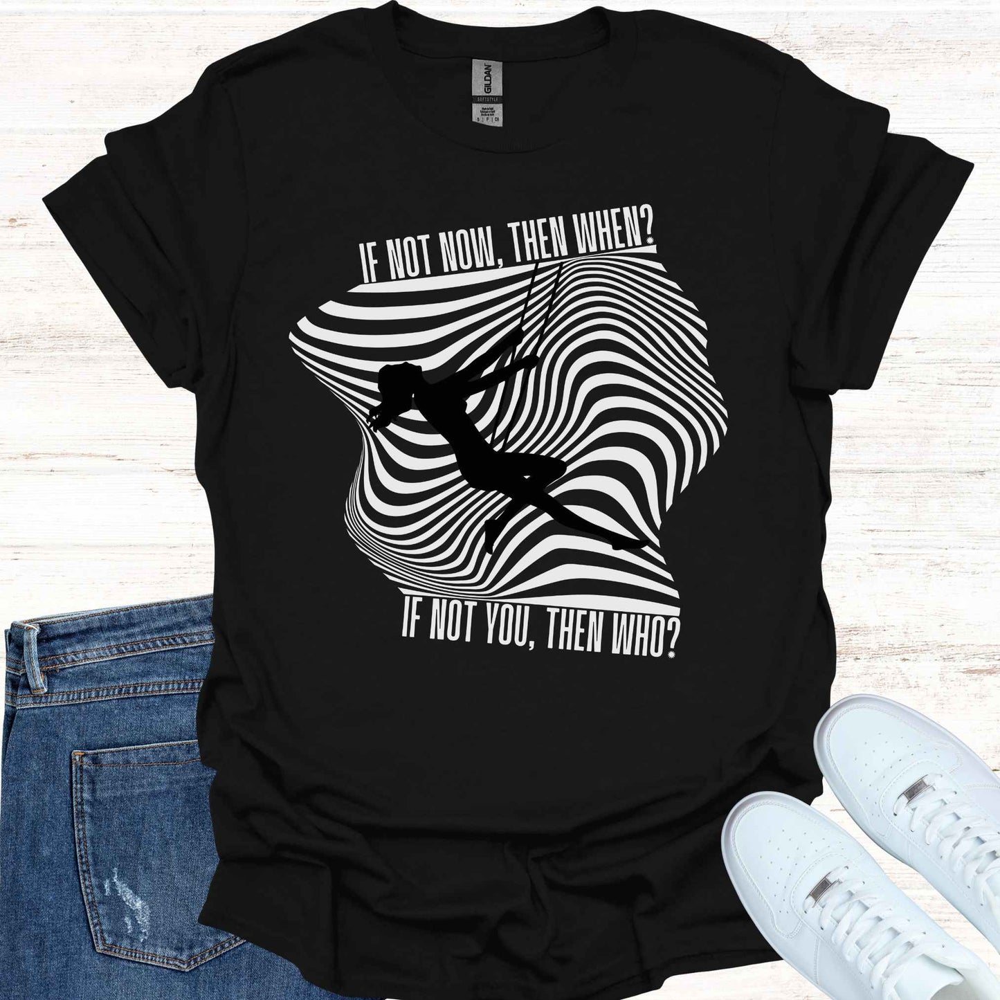 Black and white t-shirt featuring an illusory wavy pattern in the background, with the silhouette of a woman sitting on a swing. The graphic is accompanied by the empowering phrase 'If not you, then who? If not now, then when?' This design encourages confidence, self-belief, and taking action in the present moment, perfect for those on a journey of personal growth, empowerment, and self-motivation.
