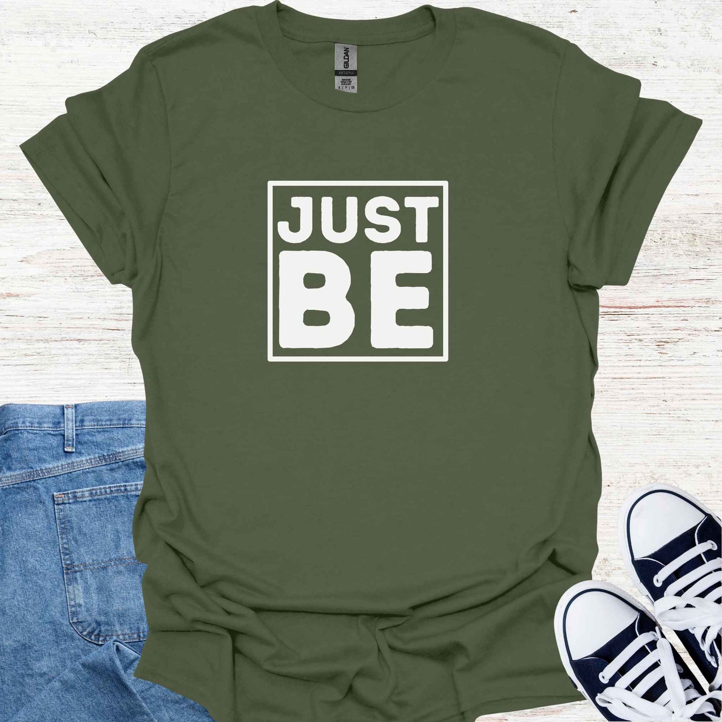 Military green t-shirt design featuring the minimalist phrase 'Just Be' in bold typography, framed for emphasis. The design conveys a profound spiritual message about living in the present moment, embracing simplicity, and finding peace in existence itself. It encourages mindfulness, acceptance, and the art of simply being, free from the need to do or become anything. Perfect for those drawn to spirituality, introspection, and mindful living.