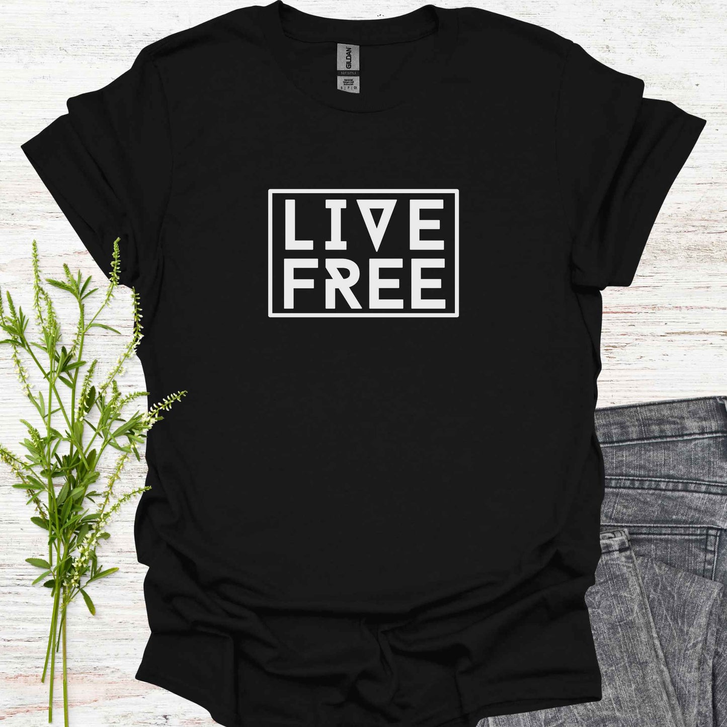 Black t-shirt featuring bold text-based design with the phrase 'Live Free' framed on a minimalist background. This design embodies the spirit of independence, self-determination, and breaking free from mental constraints. It encourages a life aligned with personal values and freedom of thought, resonating with themes of spiritual liberation, individuality, and self-empowerment.