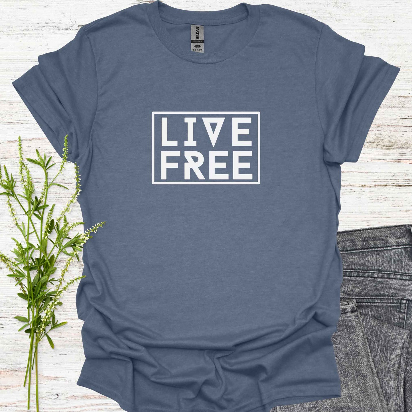Blue t-shirt featuring bold text-based design with the phrase 'Live Free' framed on a minimalist background. This design embodies the spirit of independence, self-determination, and breaking free from mental constraints. It encourages a life aligned with personal values and freedom of thought, resonating with themes of spiritual liberation, individuality, and self-empowerment.