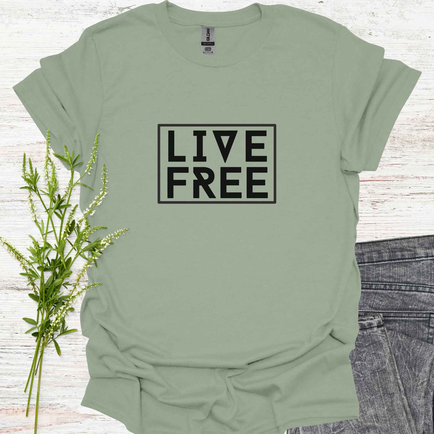 Green t-shirt featuring bold text-based design with the phrase 'Live Free' framed on a minimalist background. This design embodies the spirit of independence, self-determination, and breaking free from mental constraints. It encourages a life aligned with personal values and freedom of thought, resonating with themes of spiritual liberation, individuality, and self-empowerment.