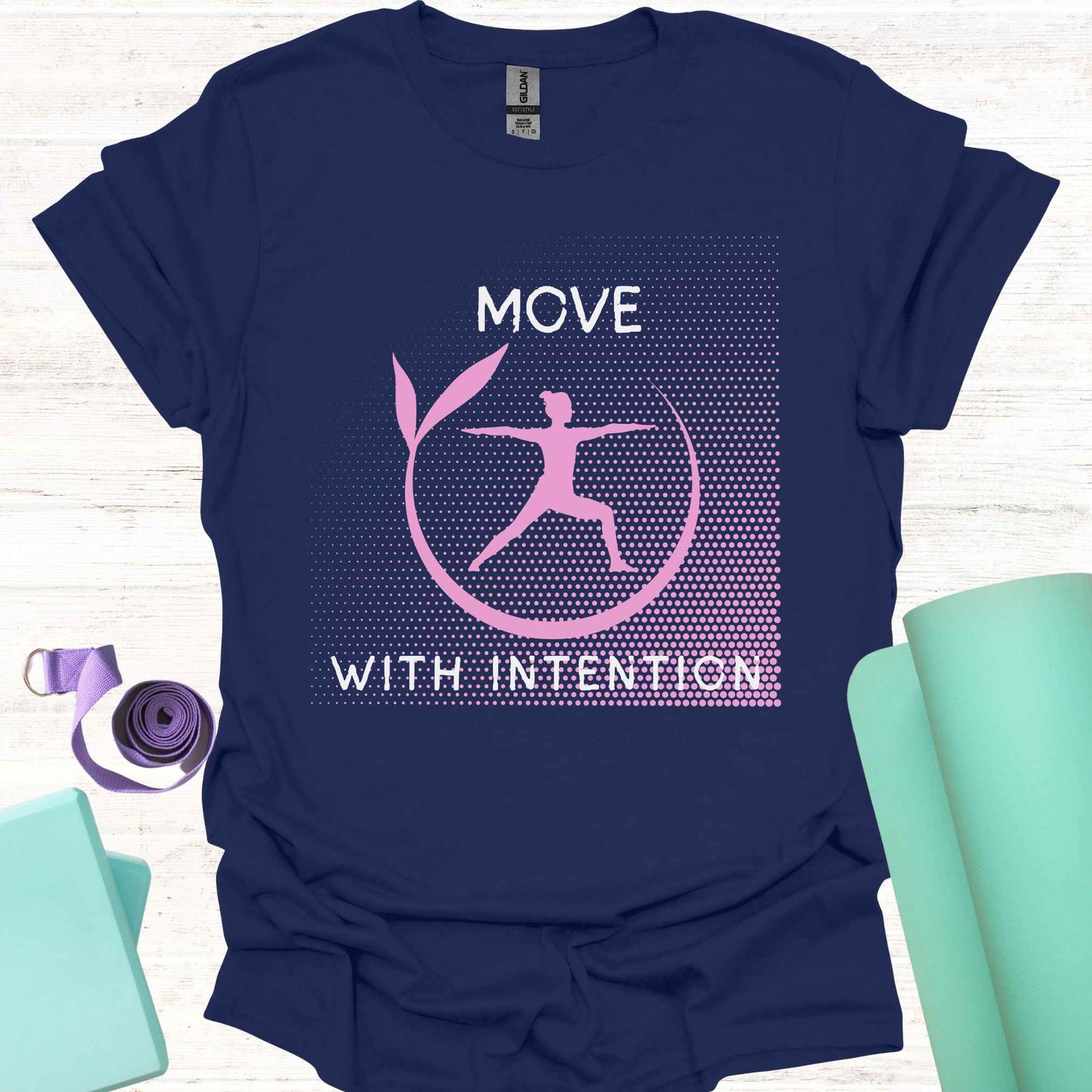 Blue t-shirt featuring a pink graphic of a figure in the yogic warrior pose, surrounded by a round frame, with the phrase 'Move with Intention.' This design embodies the central yoga teaching of mindfulness in every action, both on and off the mat. It encourages awareness, focus, and purpose in all movements, promoting balance, strength, and conscious living.