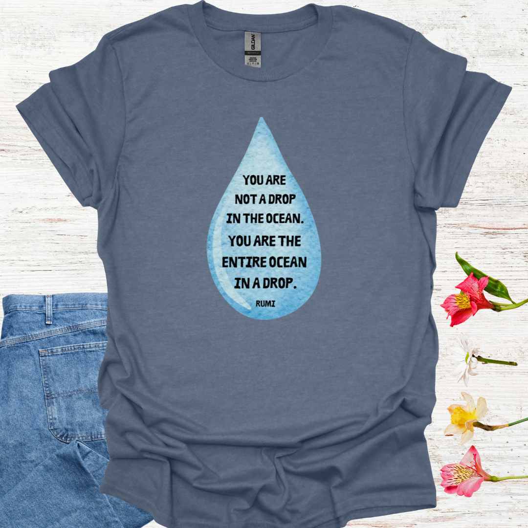 Blue t-shirt featuring design of a watercolor blue drop with the profound Rumi quote: "You are not a drop in the ocean. You are the entire ocean in a drop." The words are elegantly printed within the drop, emphasizing the metaphor of universal consciousness residing within each individual. This design symbolizes the non-dual nature of existence, reminding spiritual seekers and meditators of the infinite potential and interconnectedness within all.