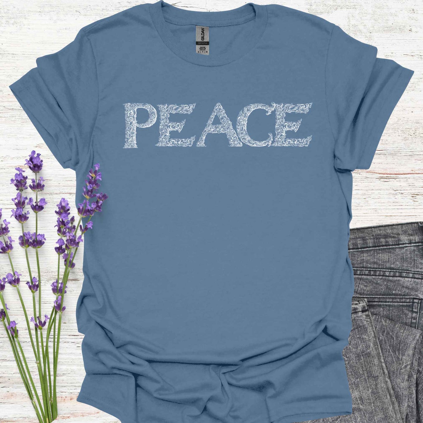 Blue t-shirt with stylized lettering of the word 'Peace' in a unique, artistic font. This design embodies the concept of inner peace, harmony, and tranquility. Perfect for those who value calmness, mindfulness, and positivity. A reminder to cultivate peace within and spread it to the world.