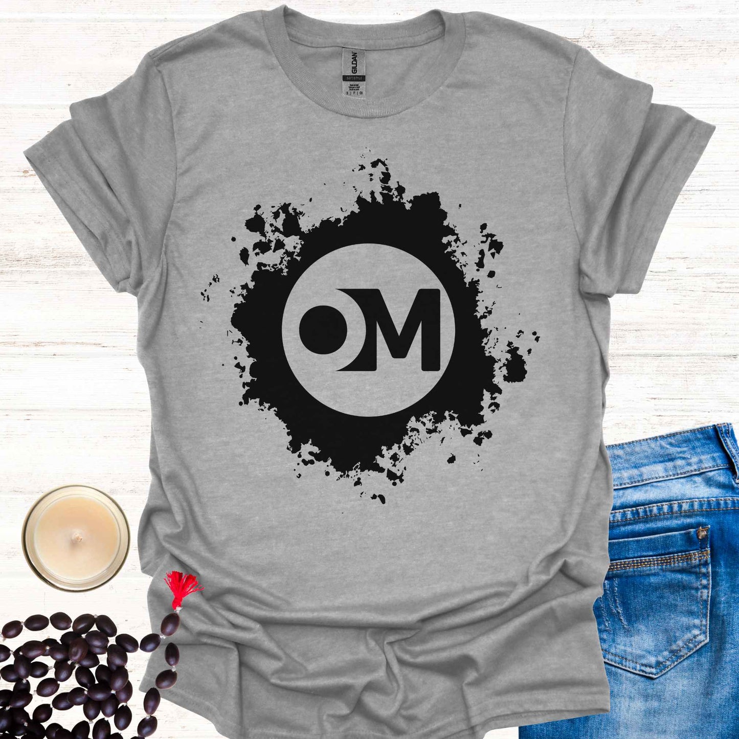 Grey t-shirt featuring the word 'OM' at the center of a black abstract graphic. Om is a sacred sound and symbol representing universal vibration, interconnectedness, and divine energy. This design invites inner peace, mindfulness, and spiritual harmony, ideal for meditators and yogis.