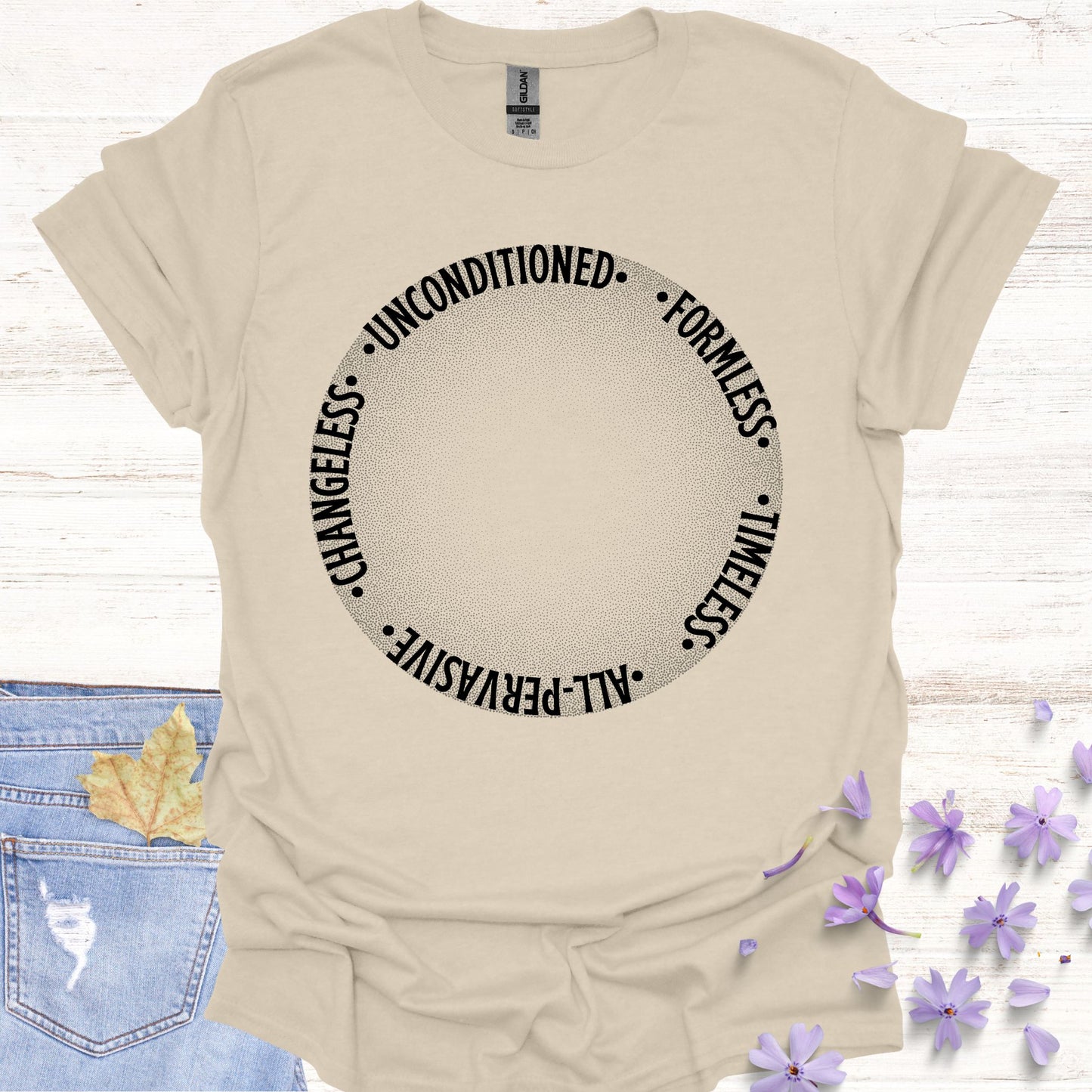 Beige t-shirt featuring a design with a round gradient background that fades from dark to white at the center. Encircling the inner edges of the circle are the words: 'timeless, all-pervasive, changeless, unconditioned, formless.' The design symbolizes the infinite and eternal nature of awareness, untouched by the limitations of time and space. It reflects the spiritual knowledge of the formless essence that underlies all existence. Ideal for those drawn to meditation, non-duality, and deep introspection.