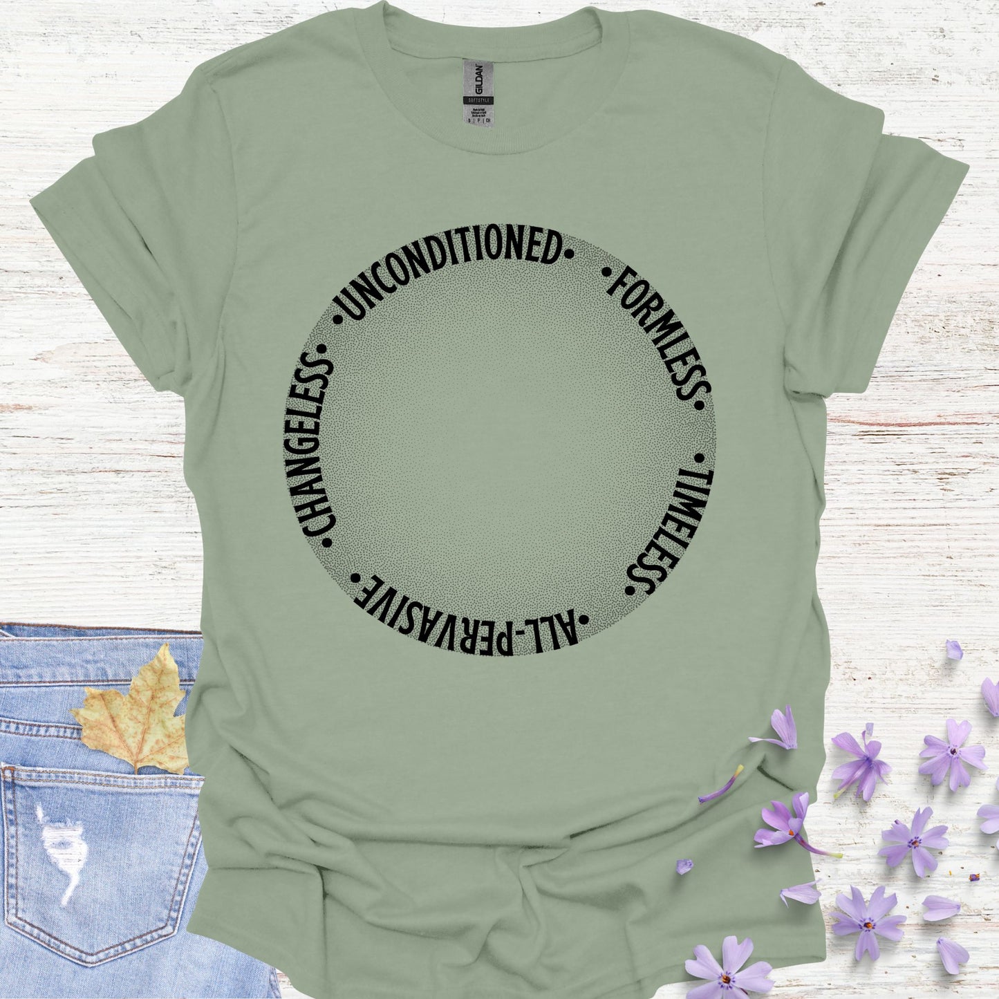 Sage green t-shirt featuring a design with a round gradient background that fades from dark to white at the center. Encircling the inner edges of the circle are the words: 'timeless, all-pervasive, changeless, unconditioned, formless.' The design symbolizes the infinite, eternal nature of awareness, untouched by the limitations of time and space. It reflects the spiritual knowledge of the formless essence that underlies all existence. Ideal for those drawn to meditation, non-duality, and deep introspection.