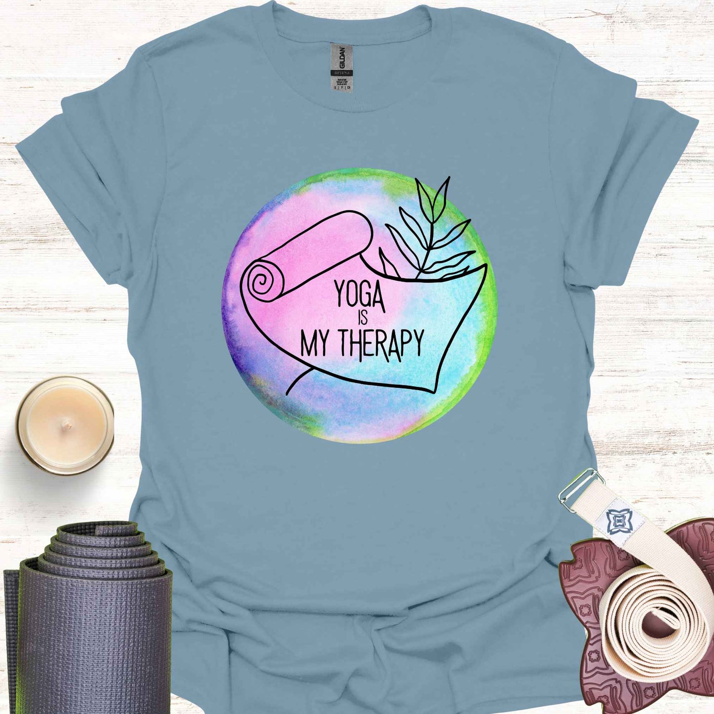 Blue t-shirt featuring a graphic of a yoga mat placed on a round, colorful watercolour background, with the phrase 'Yoga is My Therapy.' This design highlights the therapeutic power of yoga, promoting physical and mental well-being, relaxation, and mindfulness. Perfect for those who turn to yoga as a form of self-care, stress relief, and personal healing.