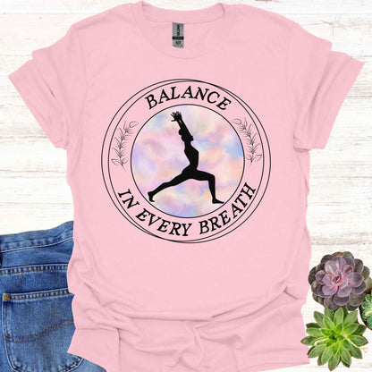 Light pink t-shirt featuring a round frame enclosing the silhouette of a person in a yoga pose, surrounded by the phrase 'Balance in Every Breath.' This design embodies the yogic teaching of cultivating awareness in both movement and breath, promoting mindfulness, harmony, and inner peace. Ideal for yoga enthusiasts and those seeking balance and calm in their daily lives.