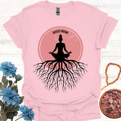 Light pink t-shirt featuring a graphic of deep tree roots extending downward, with the form of a meditating person sitting on top, suggesting that the roots belong to the meditator. This design symbolizes the yogic teaching of keeping awareness within, grounding oneself in inner peace, and embodying wisdom through meditation and spiritual practice