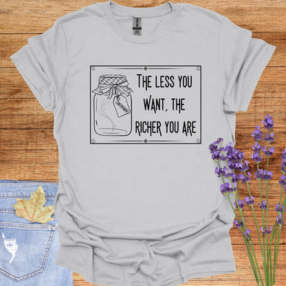 Grey t-shirt featuring a framed black-and-white graphic of an empty jar labelled 'Contentment,' paired with the minimalist phrase 'The Less You Want, The Richer You Are.' This design symbolizes detachment, inner fulfillment, and the spiritual ideal of finding inner richness through desirelessness.